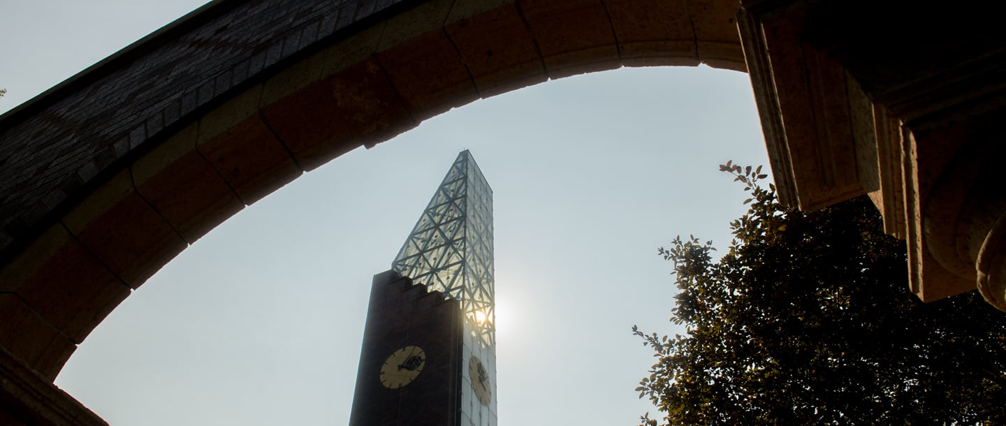 A worms-eye view of the bell tower from under the arch. You can see the arch above you framing the bell tower, and the sun shines through the bell tower's glass.
